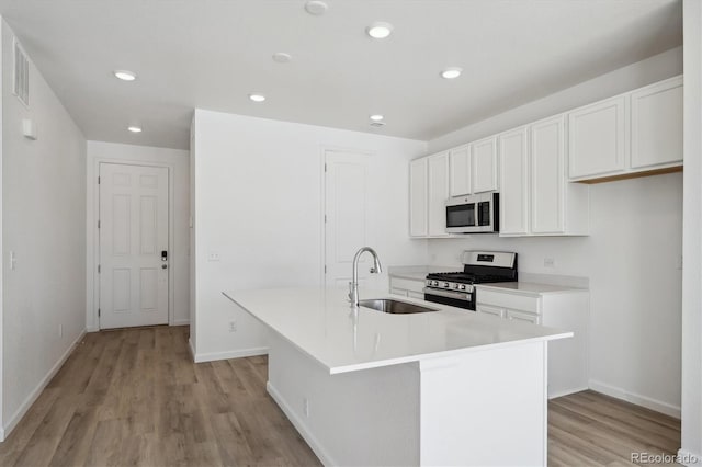 kitchen featuring appliances with stainless steel finishes, sink, an island with sink, and white cabinetry