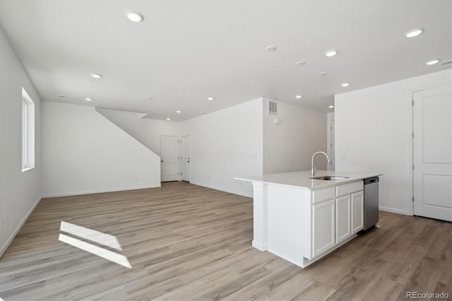 kitchen with an island with sink, white cabinetry, sink, and light hardwood / wood-style floors