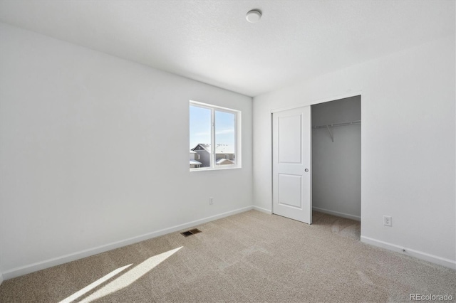 unfurnished bedroom featuring light carpet and a closet