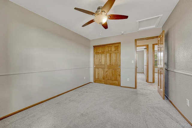 unfurnished bedroom with attic access, carpet floors, ceiling fan, baseboards, and a closet