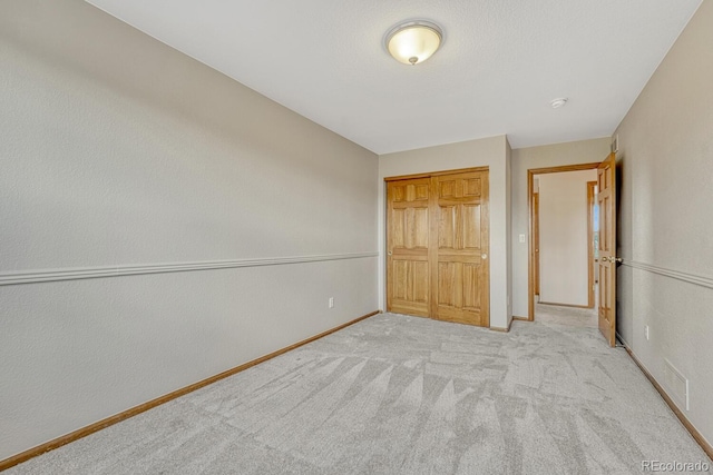 unfurnished bedroom with baseboards, carpet, and a closet