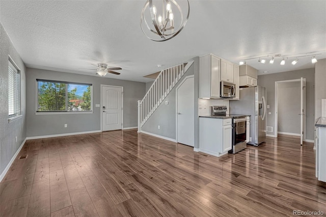 201 S Boundary St, Woodland Park, CO 80863 - unfurnished living room featuring dark wood-style floors, a ceiling fan, stairway, a chandelier, and a textured ceiling