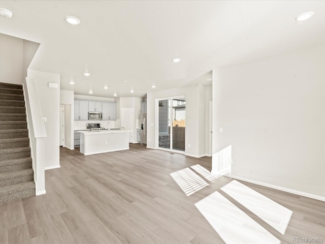 unfurnished living room featuring sink and light hardwood / wood-style flooring