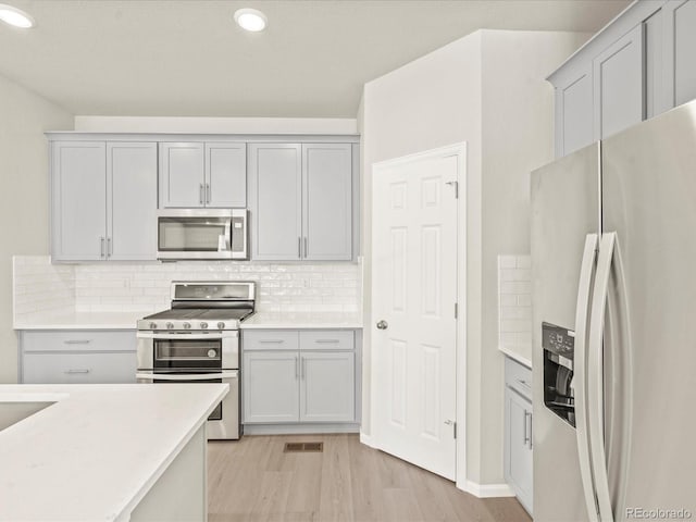 kitchen featuring stainless steel appliances, backsplash, and light hardwood / wood-style flooring