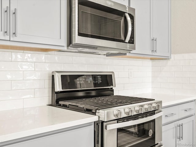 kitchen with stainless steel appliances, tasteful backsplash, and white cabinetry