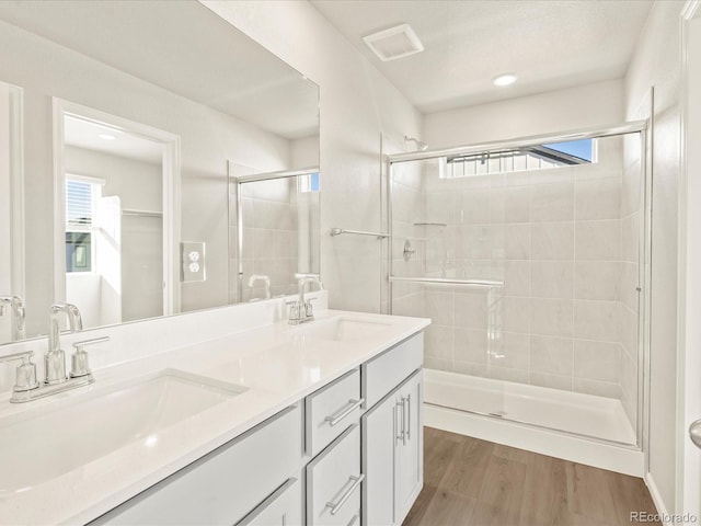 bathroom with walk in shower, wood-type flooring, vanity, and plenty of natural light