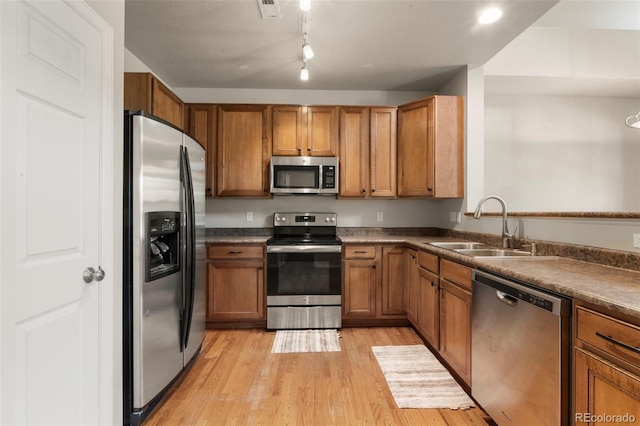 12778 Jasmine St Unit E, Thornton, CO 80602 - kitchen with appliances with stainless steel finishes, brown cabinets, light wood-style floors, and dark countertops