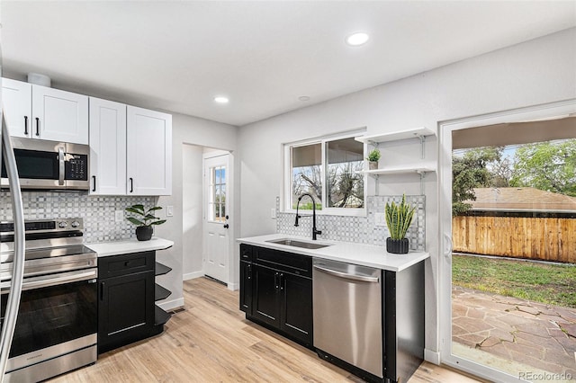 kitchen with stainless steel appliances, a sink, dark cabinets, light countertops, and recessed lighting