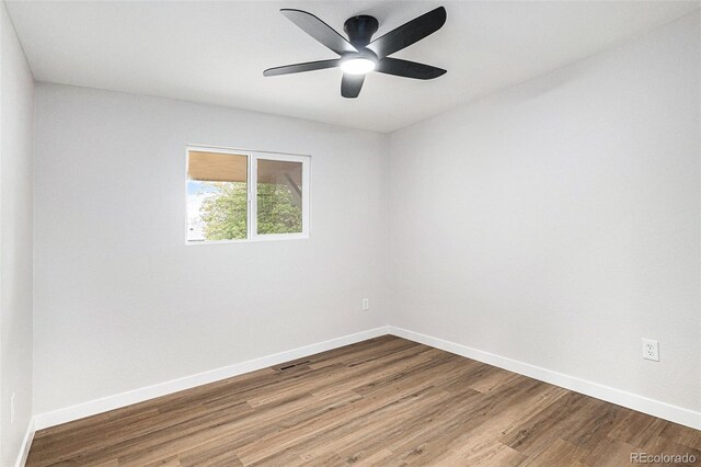 unfurnished room with baseboards, wood finished floors, and ceiling fan