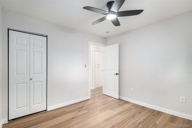 unfurnished bedroom featuring light wood finished floors, baseboards, and a closet