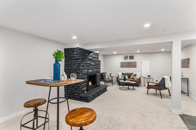 carpeted living area with a stone fireplace, baseboards, and recessed lighting