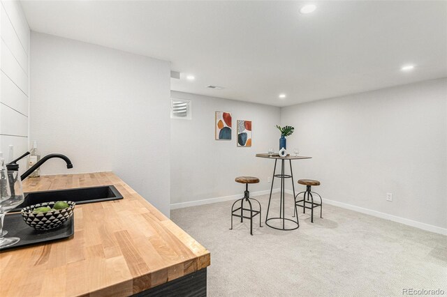 bar featuring a sink, recessed lighting, carpet flooring, and baseboards