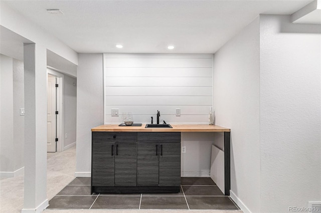 indoor wet bar with recessed lighting, dark tile patterned floors, and baseboards