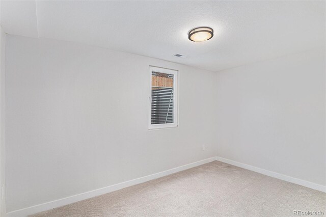 carpeted empty room featuring baseboards and a textured ceiling