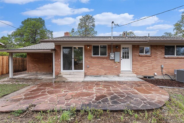 rear view of property with entry steps, fence, brick siding, central AC, and a chimney