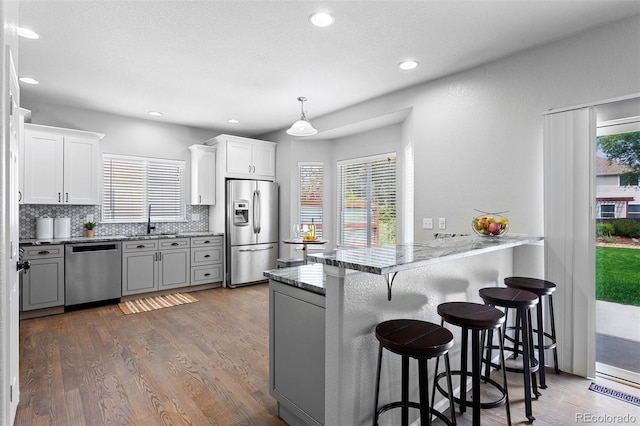 3775 Balderas St, Brighton, CO 80601 - kitchen featuring stainless steel appliances, a peninsula, a kitchen bar, dark wood-type flooring, and white cabinets