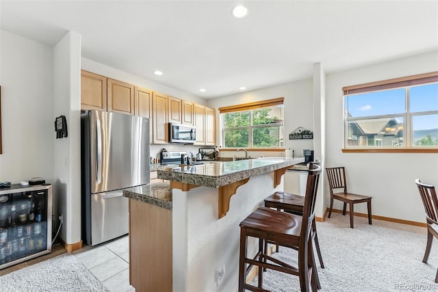 60 Black Diamond Trl Unit 60D, Silverthorne, CO 80498 - kitchen with appliances with stainless steel finishes, tile countertops, a breakfast bar area, light brown cabinets, and recessed lighting