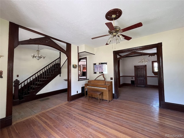 interior space featuring dark hardwood / wood-style flooring, a textured ceiling, and ceiling fan with notable chandelier