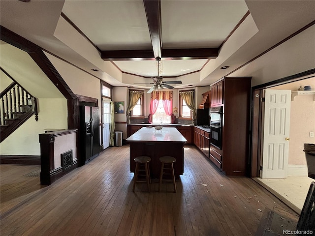 unfurnished dining area featuring dark hardwood / wood-style flooring, beamed ceiling, a tray ceiling, sink, and ceiling fan