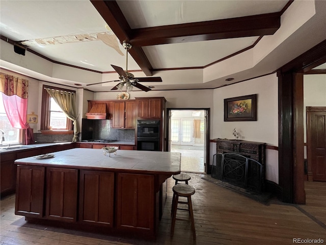 kitchen with tile counters, plenty of natural light, premium range hood, and dark hardwood / wood-style floors