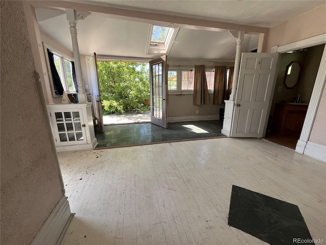 foyer with wood-type flooring, ornate columns, and a skylight