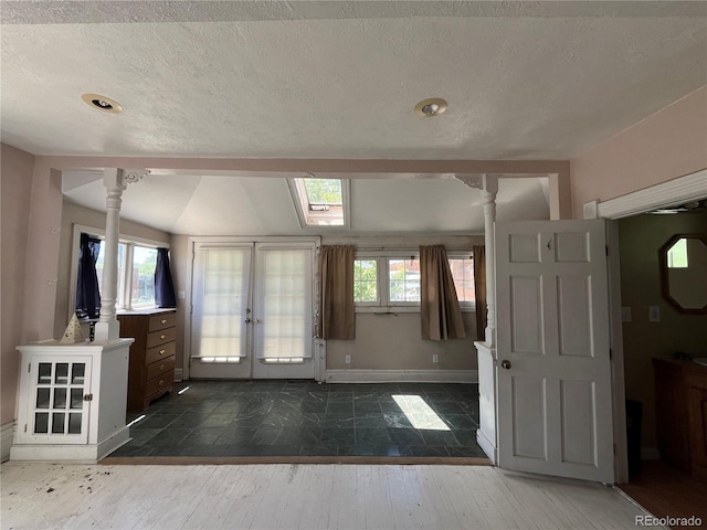 entrance foyer with french doors, decorative columns, dark tile flooring, and a textured ceiling