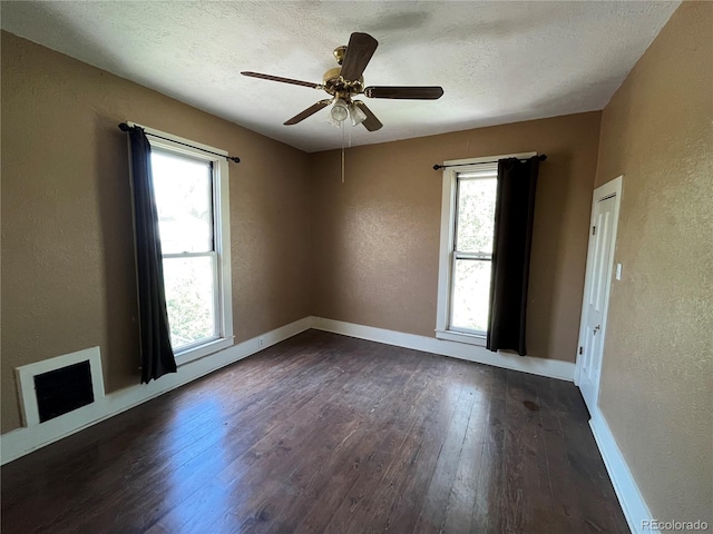 unfurnished room featuring a wealth of natural light, ceiling fan, and dark hardwood / wood-style floors