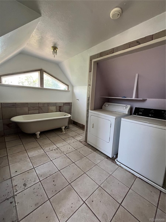 washroom featuring washing machine and dryer, a textured ceiling, and light tile floors