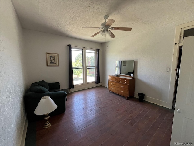 sitting room with dark wood-type flooring, ceiling fan, and a textured ceiling