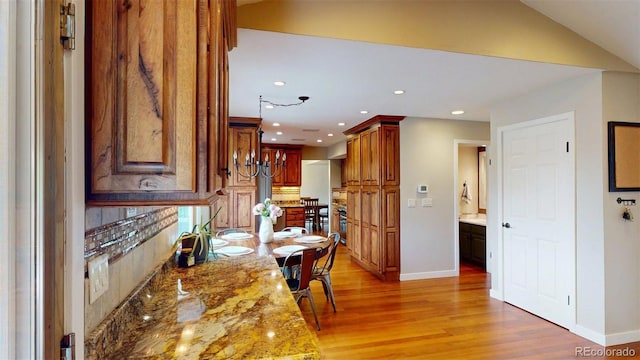 6278 E Euclid Ave, Centennial, CO 80111 - kitchen featuring light wood-style floors, baseboards, recessed lighting, light stone counters, and brown cabinets