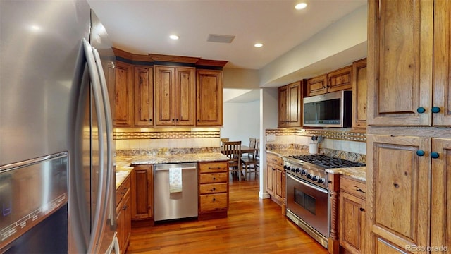 6278 E Euclid Ave, Centennial, CO 80111 - kitchen featuring appliances with stainless steel finishes, backsplash, brown cabinetry, light wood-style flooring, and recessed lighting