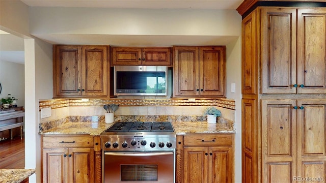 6278 E Euclid Ave, Centennial, CO 80111 - kitchen with stainless steel appliances, brown cabinets, decorative backsplash, and light stone counters
