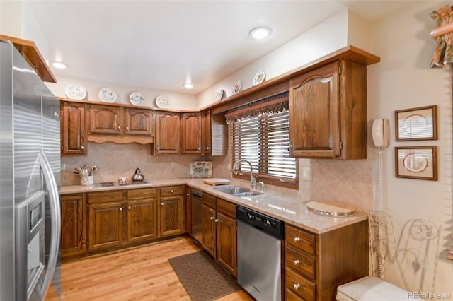 kitchen featuring sink, light wood-type flooring, stainless steel appliances, light stone countertops, and decorative backsplash