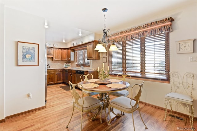 dining area featuring a wealth of natural light, a notable chandelier, and light hardwood / wood-style floors