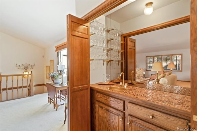 bar with vaulted ceiling, sink, and light carpet