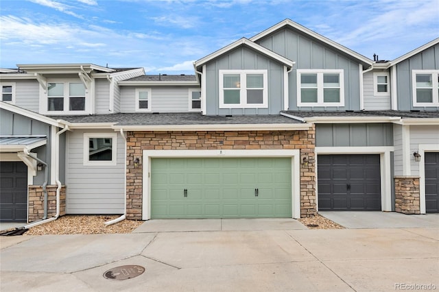 view of property with an attached garage, stone siding, board and batten siding, and concrete driveway