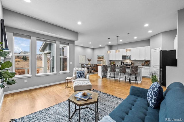 living room featuring baseboards, light wood-type flooring, and recessed lighting