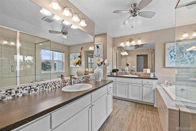 bathroom with a garden tub, two vanities, a sink, and visible vents