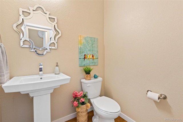 half bath with baseboards and toilet