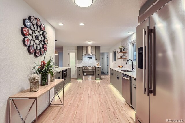 10698 W 26th Ave, Lakewood, CO 80215 - kitchen with premium appliances, wall chimney range hood, light wood finished floors, light countertops, and a sink