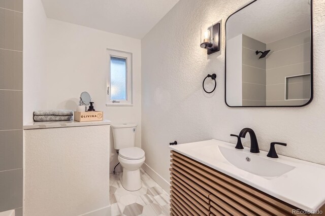 10698 W 26th Ave, Lakewood, CO 80215 - bathroom featuring toilet, a textured wall, baseboards, a shower, and vanity