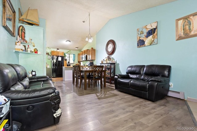 living room featuring hardwood / wood-style floors, a chandelier, vaulted ceiling, and a baseboard heating unit