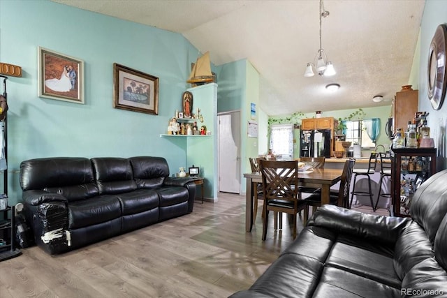 living room with an inviting chandelier, hardwood / wood-style flooring, lofted ceiling, and a textured ceiling