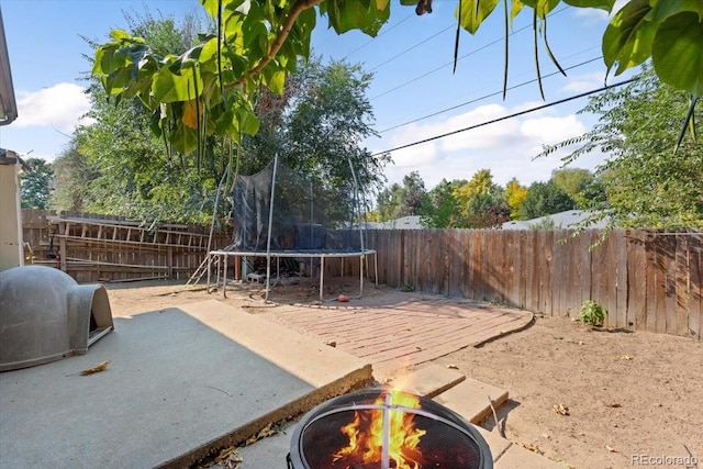 exterior space with a trampoline and an outdoor fire pit