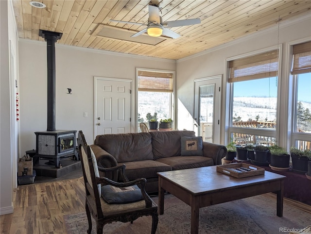 living room with ceiling fan, wood-type flooring, a wood stove, and wooden ceiling