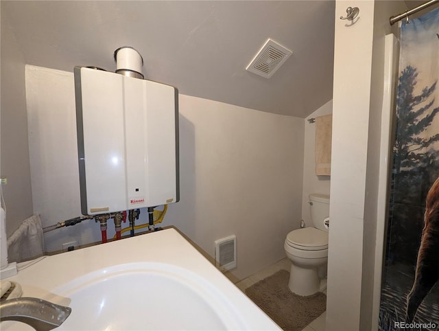 bathroom with lofted ceiling, sink, tankless water heater, toilet, and tile patterned floors