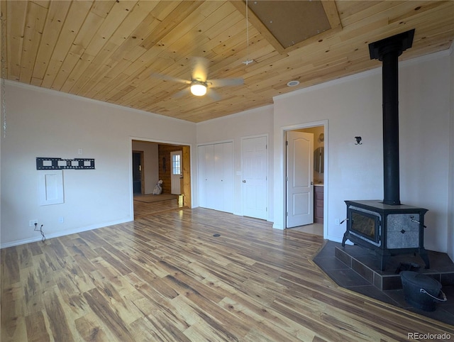 unfurnished living room featuring crown molding, wood finished floors, a ceiling fan, a wood stove, and wood ceiling