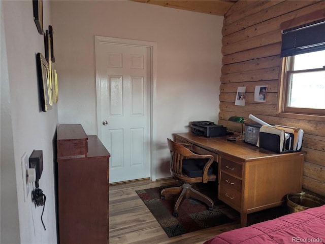 bedroom with log walls and wood finished floors