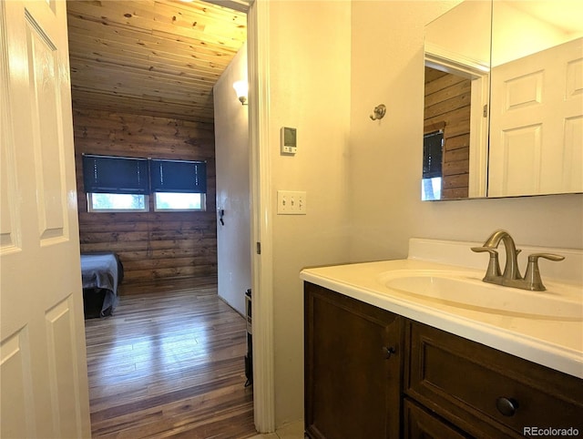 bathroom with rustic walls, vanity, wood finished floors, and wooden ceiling