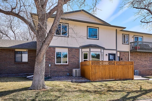 back of property featuring brick siding, central AC unit, and a lawn